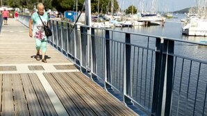 A wooden pier with a metal railing, leading to a marina with boats. - La Guguenaie (Beganne)