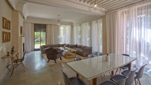 A spacious living room with a large sectional sofa, a glass dining table, and a chandelier. - Villa Touareg Domaine des Kasbahs (Marrakech)