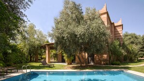 Ein Pool mit einer Pergola und einem Gebäude mit markanter Architektur.