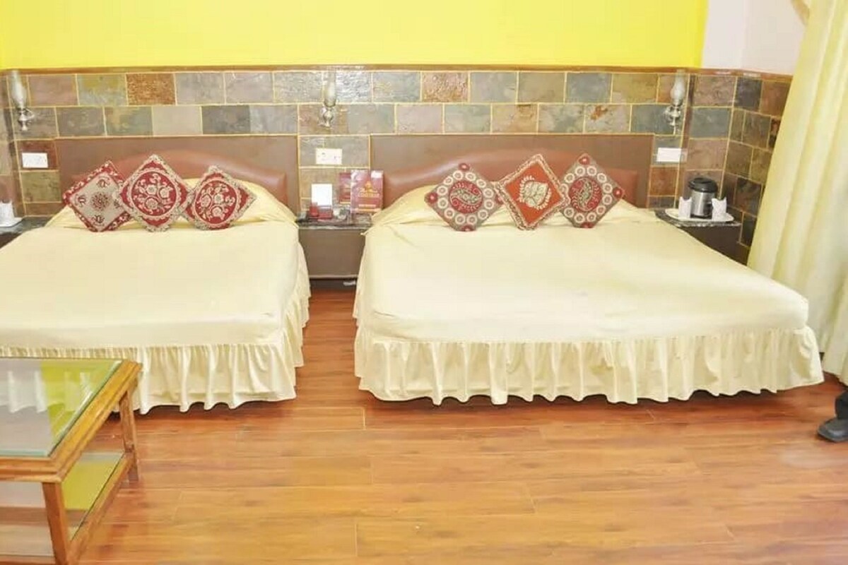Una habitación de hotel con dos camas, una mesita pequeña y una pared con azulejos.