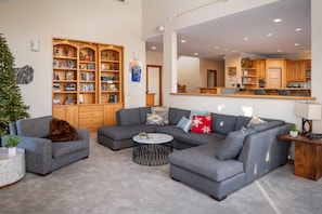 Un salon moderne avec un canapé d’angle, une table basse et une bibliothèque.