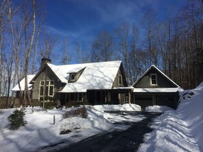 A large, two-story house with a steeply pitched roof, surrounded by a snowy landscape and trees. - Extra Lg 4 Bed & 5 1/2. BA, Great for families & couples! (Highlands)