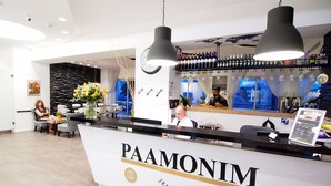 A hotel reception area with a PAAMONIM Jerusalem Hotel sign, a bar with bottles, and a seating area with a clock and flowers. - Paamonim Studios - Adults only (Jerusalem)