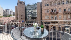 A balcony with a table, chairs, and a bottle of wine. - Paamonim Studios - Adults only (Jerusalem)