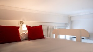 A bed with white bedding and red pillows, a bedside lamp, and a white headboard. - Paamonim Studios - Adults only (Jerusalem)