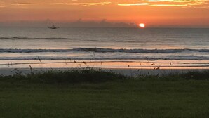 Un atardecer sobre el océano con un primer plano de hierba.