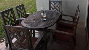 Una mesa y sillas de madera en un patio con vista al océano.