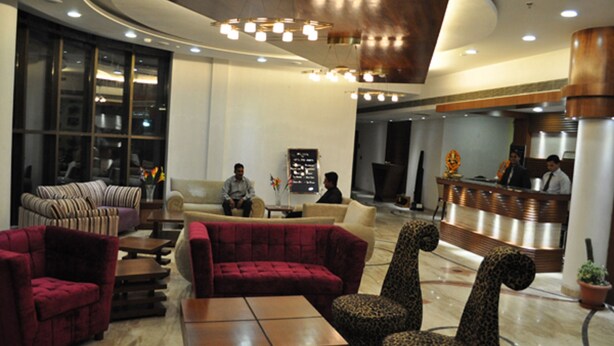 A modern lobby with plush seating, a reception desk, and a large window. - Hotel The Amaris (Rishikesh)