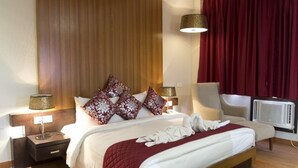 A neatly arranged bedroom with a bed, bedside tables, a chair, and a radiator. - Hotel The Amaris (Rishikesh)