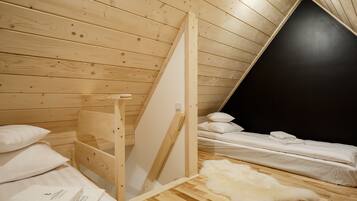 A small, wooden-paneled room with a loft bed, a white fur rug, and a black wall.