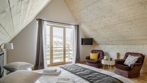 A bedroom with a large bed, two chairs, a small table, and a TV. - Tatra Wood House (Zakopane)