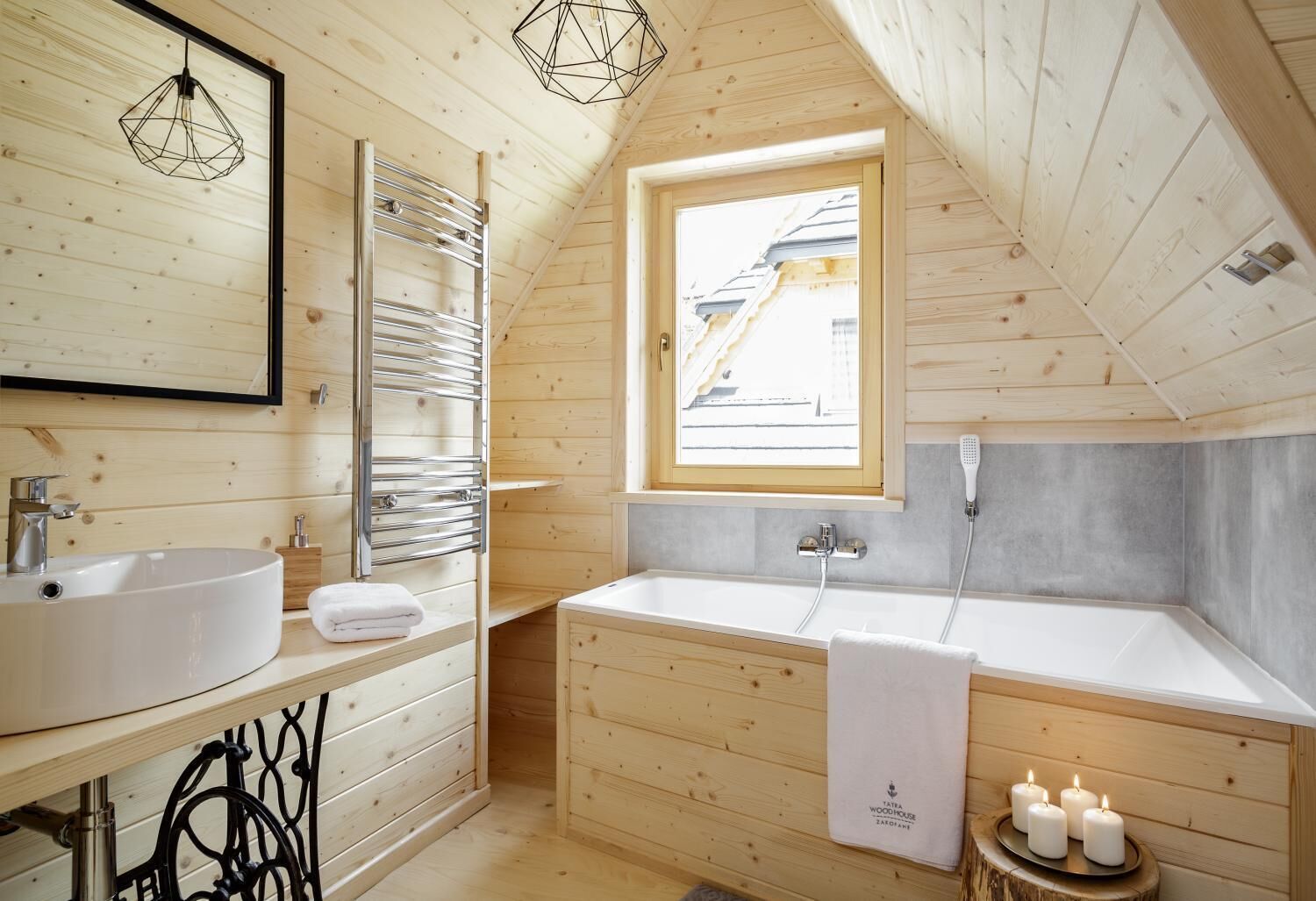 A wooden cabin bathroom with a skylight, two sinks, a bathtub, and a towel rack.
