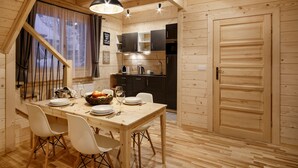 Un interior de madera con una mesa de comedor dispuesta para cuatro personas, una zona de cocina y una escalera.