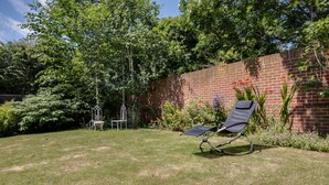 A backyard with a brick wall, a lawn, and a garden with flowers and shrubs. - The Annexe (Cheltenham)