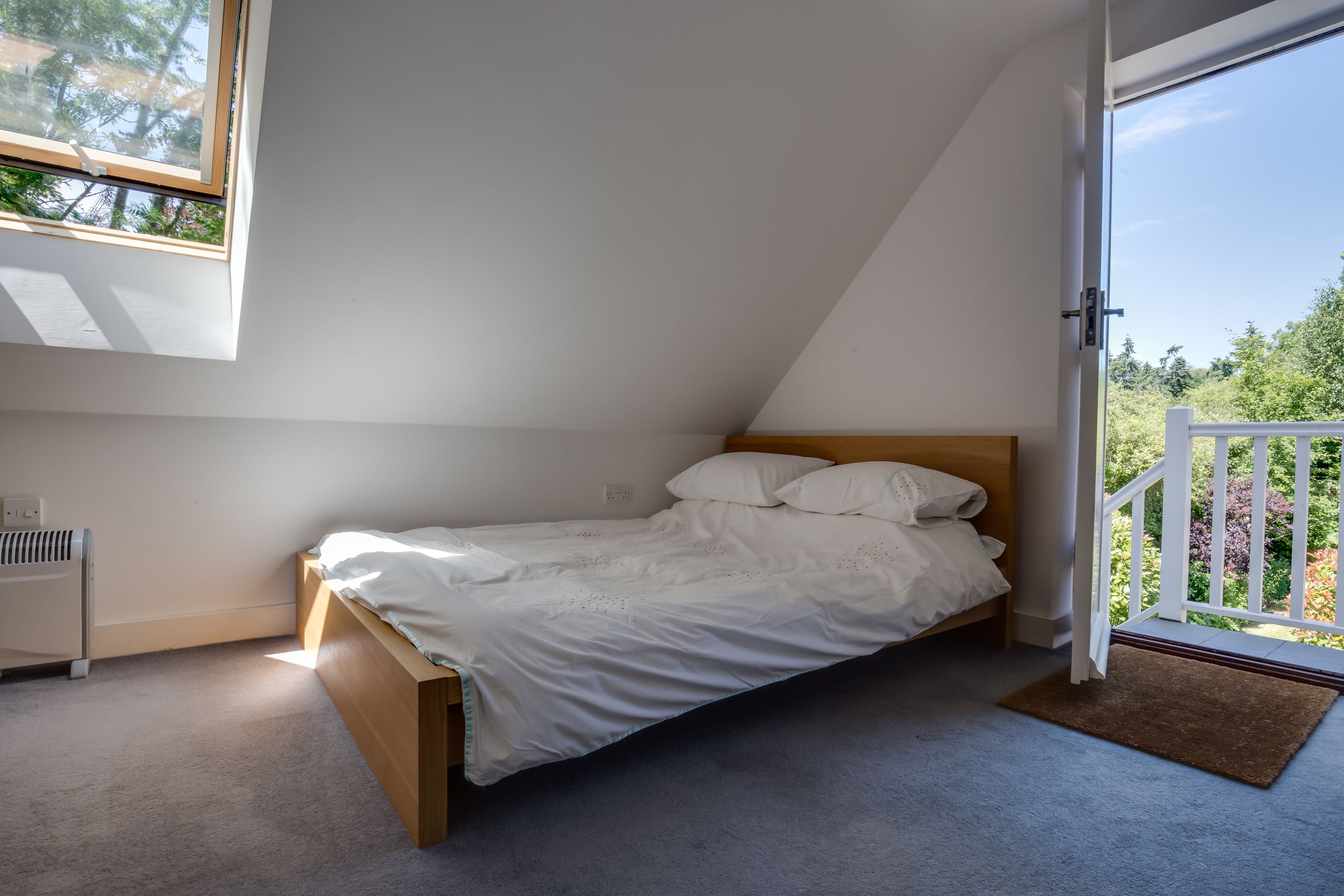 Une chambre avec un lit simple, un radiateur et une fenêtre donnant sur un balcon.