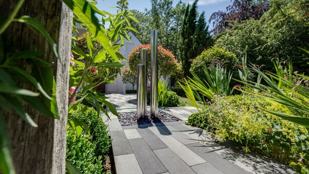 A garden pathway with a wooden fence, metal poles, and various plants. - The Annexe (Cheltenham)
