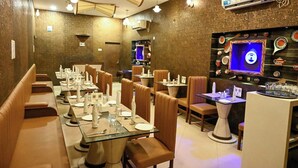 A restaurant with long communal tables, individual booths, and a bar area. - Hotel Baidyanath (Deoghar)