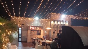 An outdoor dining area with string lights, a sign reading 'Prangan,' and tables set for dining. - Hotel Baidyanath (Deoghar)