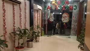 A hallway with potted plants, a star-shaped ceiling decoration, and festive decorations. - Hotel Baidyanath (Deoghar)