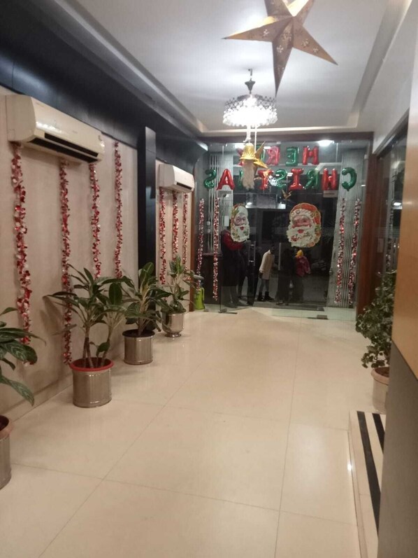A hallway with potted plants, a star-shaped ceiling decoration, and festive decorations. - Hotel Baidyanath (Deoghar)