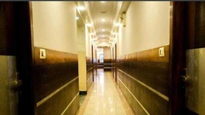 A long, narrow hallway with a tiled floor and wooden paneling on the walls. - Hotel Baidyanath (Deoghar)