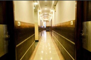 Un pasillo largo y estrecho con suelo de baldosas y paneles de madera en las paredes.