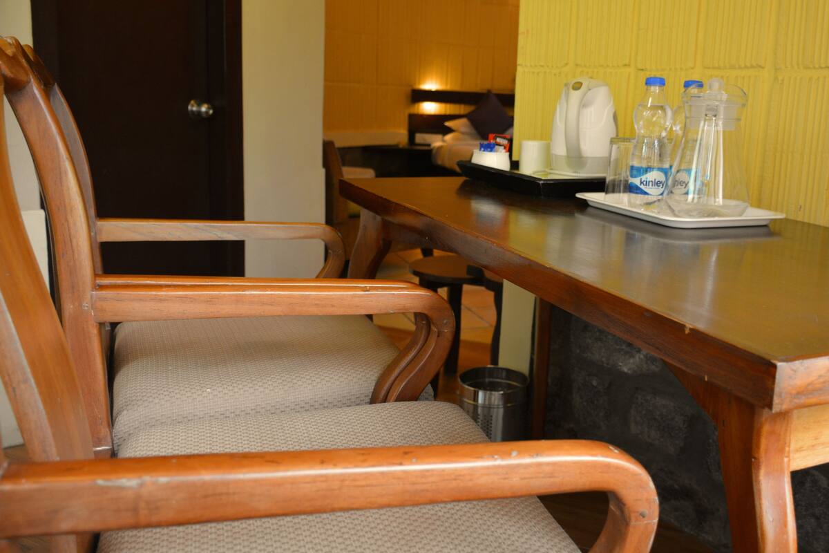 A wooden dining table with chairs, a coffee maker, and a tray with water bottles.