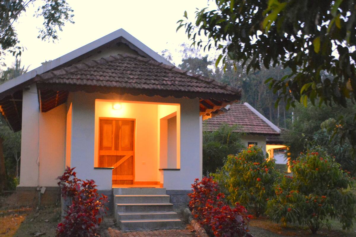 A small house with a tiled roof, a visible door, and steps leading to the entrance.