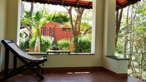 Una habitación con un ventanal grande, un banco de madera y vistas a un edificio rojo y follaje verde.
