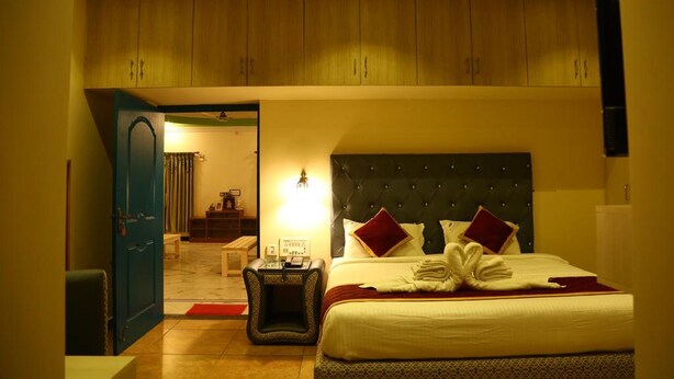 Une chambre d’hôtel avec un lit, une table de chevet, un ventilateur de plafond et des placards en bois au-dessus du lit.