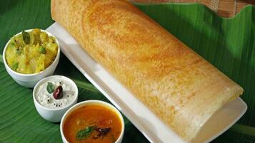 A traditional South Indian meal with a dosa, coconut chutney, sambar, and raita.