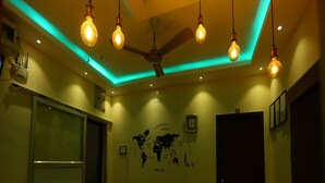 Une pièce avec un ventilateur de plafond, des ampoules suspendues, une carte du monde accrochée au mur et une porte.