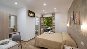 A hotel room with a bed, a desk, a chair, and a small table with food. There is a bathroom visible through an open door. - B&B Il Girasole (Agerola)