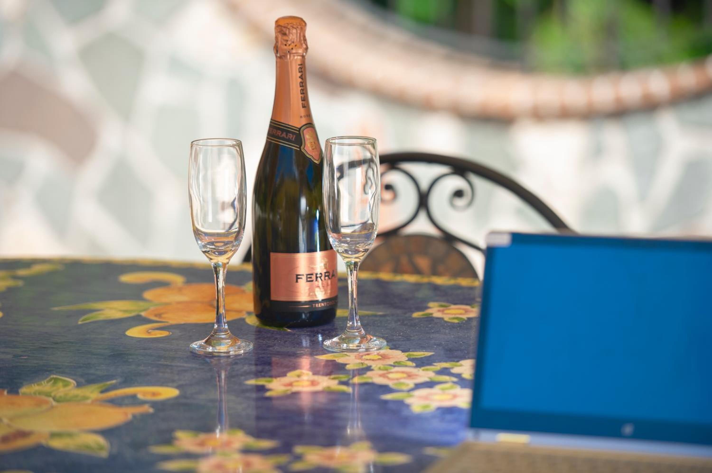 Una botella de vino y dos copas sobre una mesa con estampado floral.