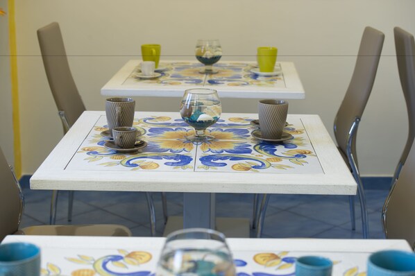 Una mesa de comedor con mantel floral, dos sillas y un vaso de agua.