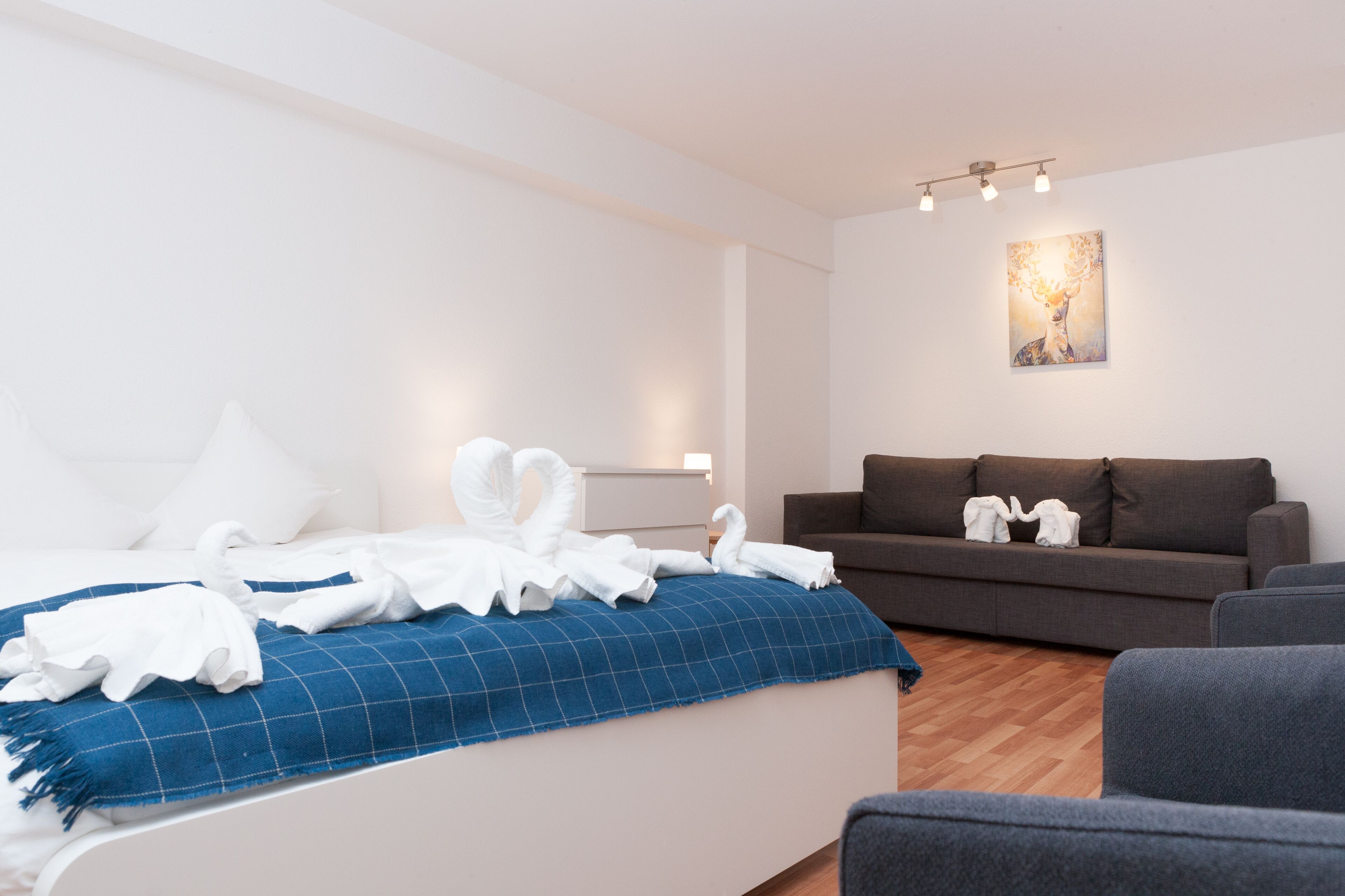 Een moderne hotelkamer met een bed, een blauw geruit kleed, een bruine bank en een schilderij aan de muur.
