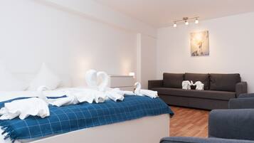 Een moderne hotelkamer met een bed, een blauw geruit kleed, een bruine bank en een schilderij aan de muur.