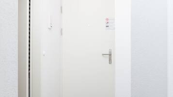 A hallway with a white door, a doorbell, and a wall-mounted light switch.