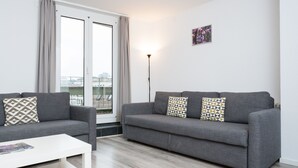 A modern living room with a grey sofa, a white coffee table, and a floor lamp. - Galaxy Apartments (Lucerne)