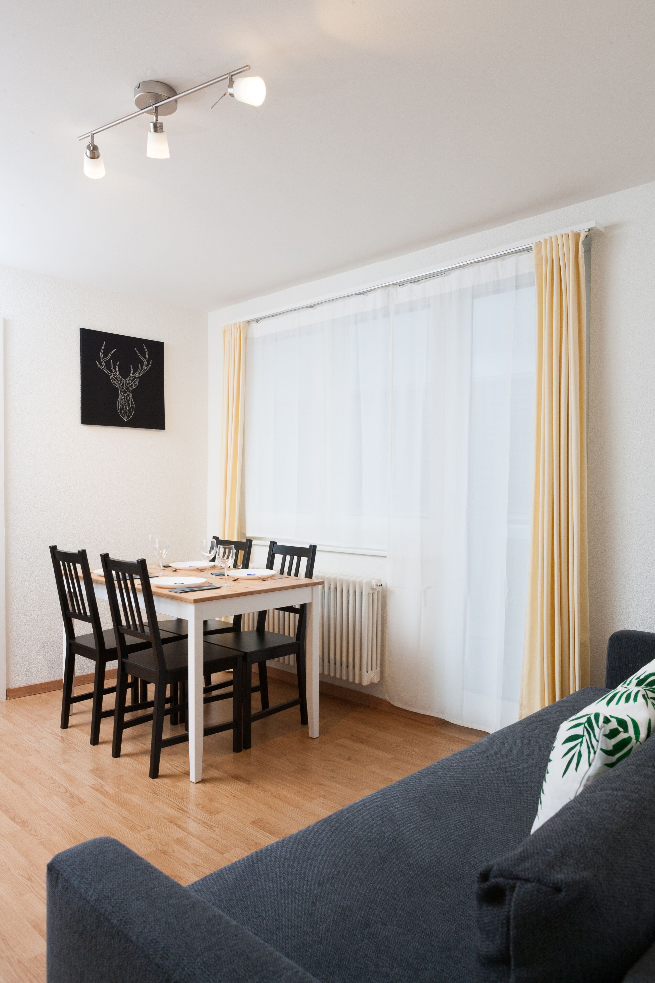 Ein Essbereich mit Tisch, Stühlen, einer Heizung und einem fenster mit Vorhängen.