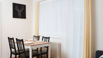 Ein Essbereich mit Tisch, Stühlen, einer Heizung und einem fenster mit Vorhängen.