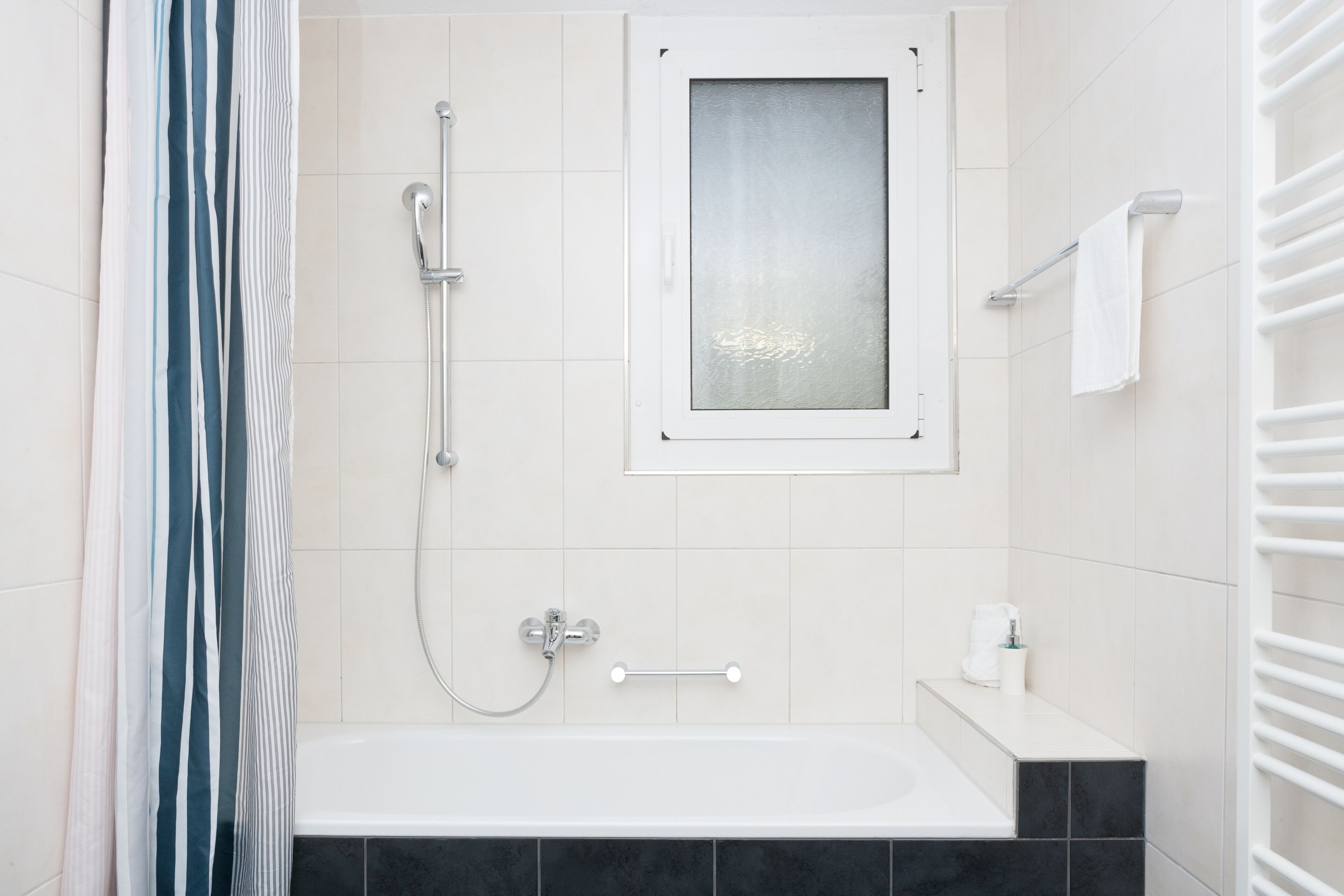Un baño moderno con bañera, ducha y ventana.