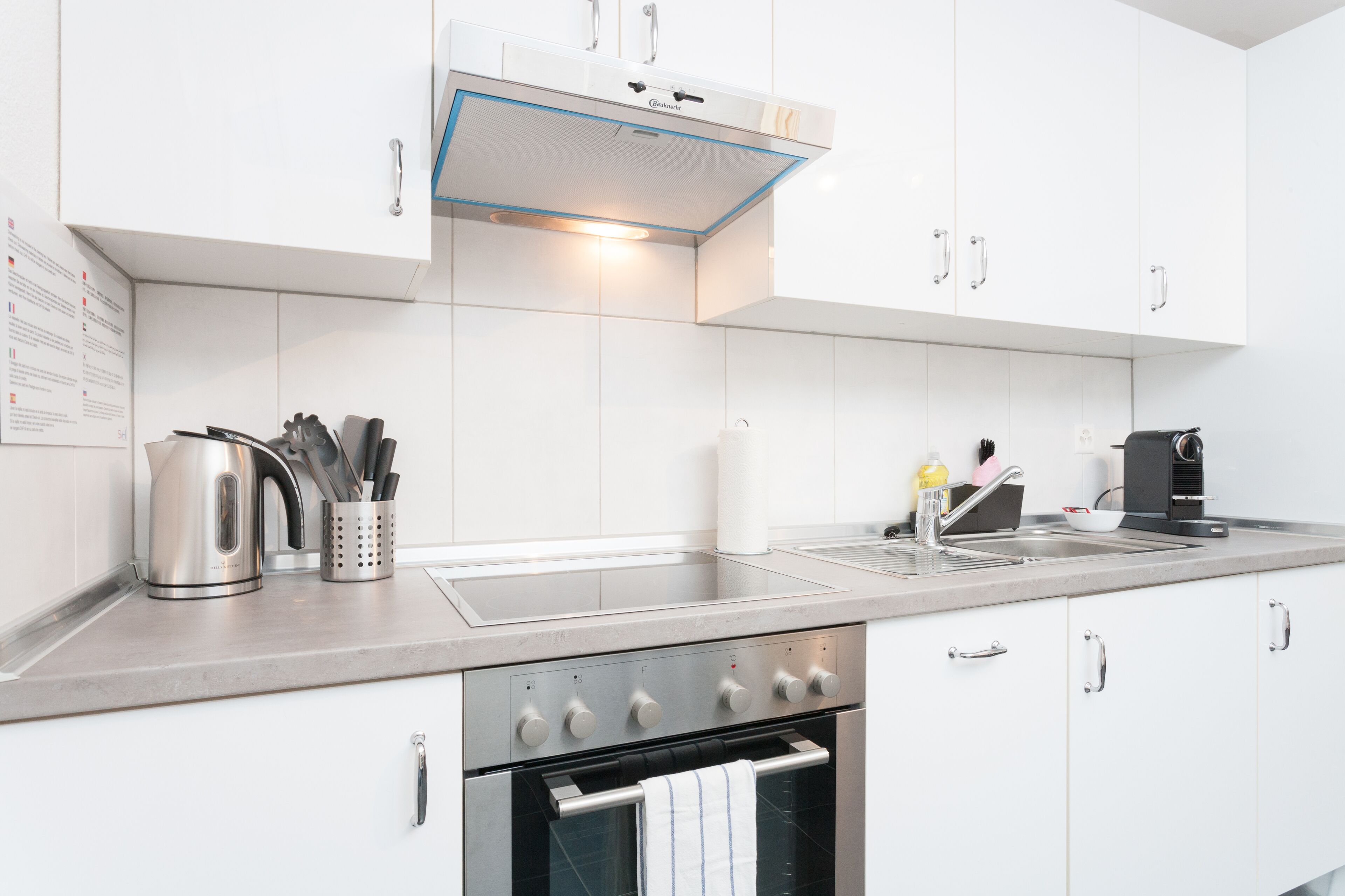 A modern kitchen with white cabinets, stainless steel appliances, and a built-in oven.