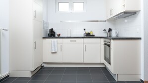 A modern kitchen with white cabinets, a black countertop, and a built-in oven. - Galaxy Apartments (Lucerne)