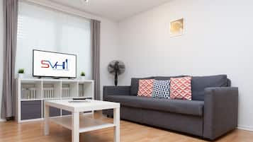 A modern living room with a grey sofa, white coffee table, and a TV displaying 'SVH Star Vacation Homes'.