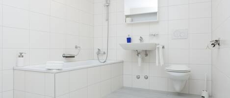 A modern bathroom with a bathtub, sink, and toilet.