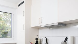 A modern kitchen with white cabinets, a black countertop, and a window providing natural light. - Galaxy Apartments (Lucerne)