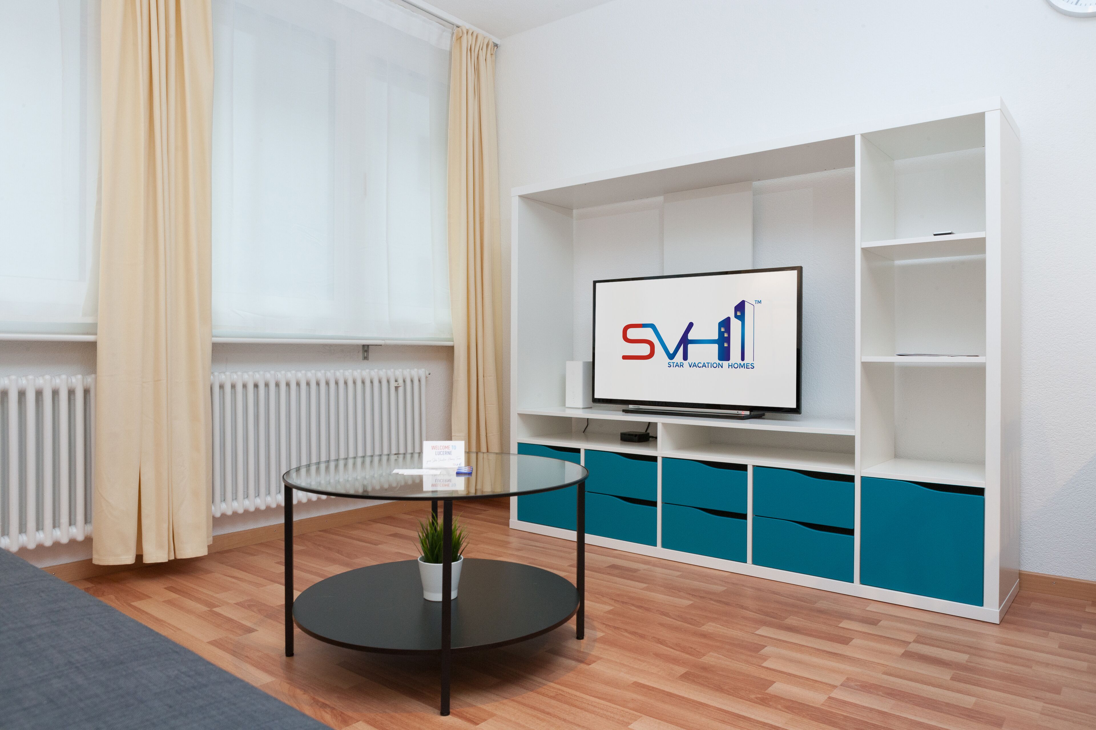 A modern living room with a television, a glass coffee table, and a blue storage unit.