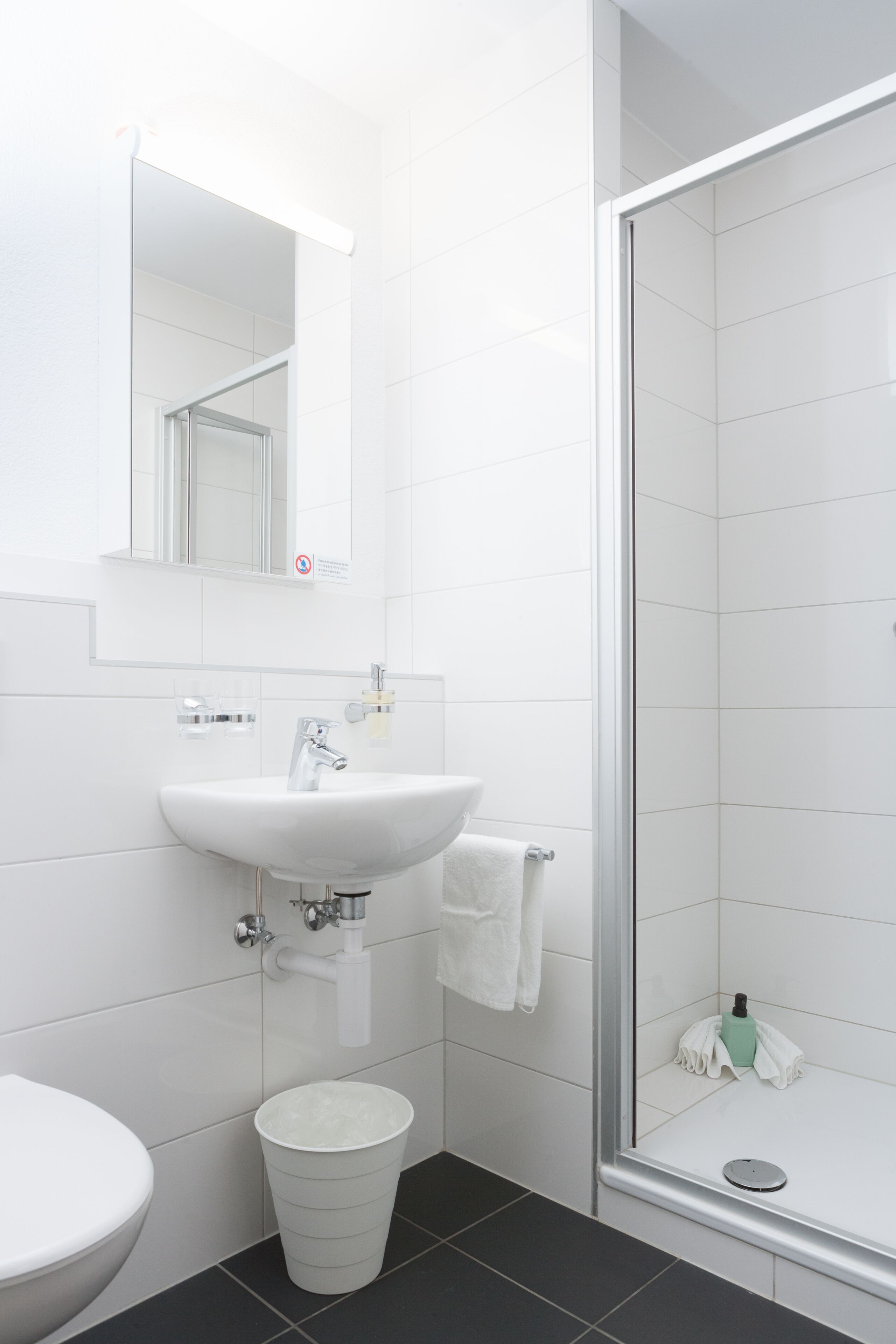 A bathroom with a white sink, mirror, and toilet.