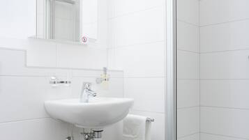 A bathroom with a white sink, mirror, and toilet.